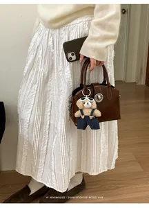 Borsa a mano retrò in pelle marrone con ciondolo a orsetto in un look lifestyle curato