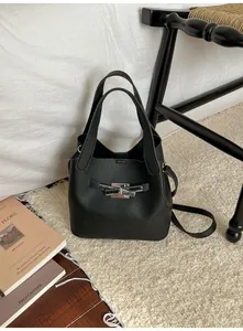 Détail du sac seau noir en cuir grainé avec fermoir argenté sur tapis moelleux