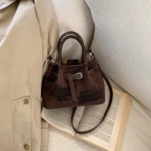 Detail of dark brown checkered bucket bag with silver buckle and detachable strap