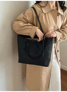 Grand sac cabas noir classique avec surface texturée porté par un mannequin