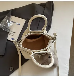 Detailed interior of the cream leather bucket bag with brown lining and plush charm