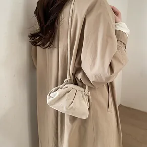 Modèle portant un sac nuage plissé beige en daim doux avec une bandoulière fine
