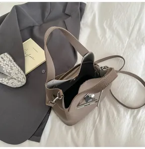 Vue de dessus d'un sac seau en cuir taupe avec fermoir argenté et veste grise