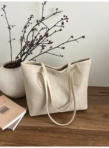 Détail du cabas blanc crème montrant la surface texturée et les fines bandoulières