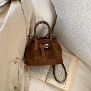 Detailed close-up of dark brown suede bucket bag texture on vintage book props