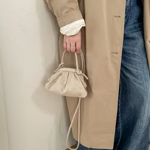 Détail du sac dumpling plissé blanc cassé avec une fine bandoulière élégante