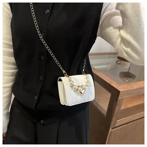 Detail of white mini crossbody bag featuring woven texture and pearl beaded handle strap