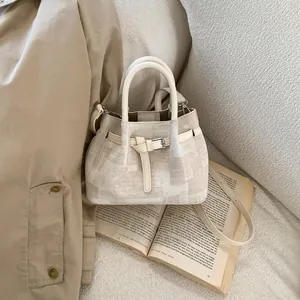 Detail view of a beige canvas bucket bag on an open book with elegant vintage styling