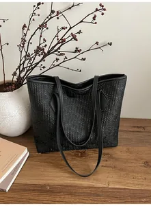 Gros plan d'un cabas noir minimaliste avec texture gaufrée sur un bureau en bois