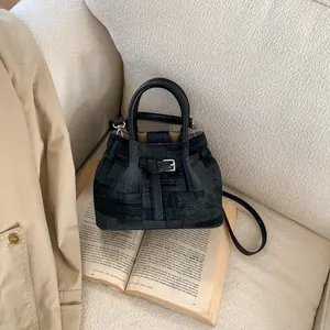 Close-up of dark denim bucket bag with leather straps on vintage book scenery