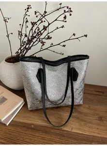 Détail d'un sac cabas argenté métallisé avec texture froissée sur une table en bois