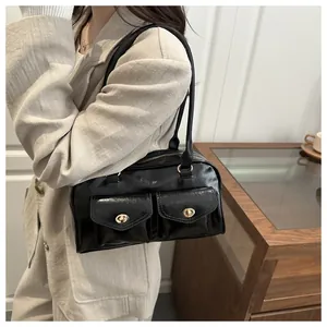 Close-up of black glossy shoulder bag with dual front pockets and gold twist-lock hardware