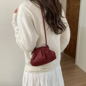 Sac à main bordeaux plissé effet mat porté avec une tenue en maille blanche