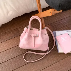 Pink fabric bucket bag with dual handles and buckle detail on a wooden chair