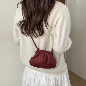 Détail du sac bandoulière plissé bordeaux porté avec un pull blanc et une jupe