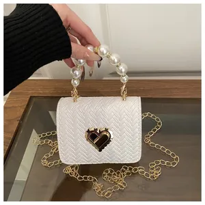 Detail of white woven mini bag featuring large pearl handle and golden heart lock