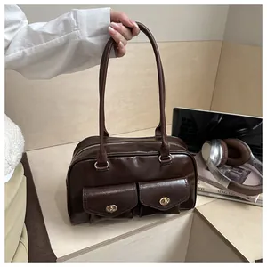 Detail of dark brown faux leather pillow bag featuring dual front pockets and gold hardware