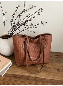 Détail du sac cabas marron avec texture en cuir matelassé vertical sur surface en bois
