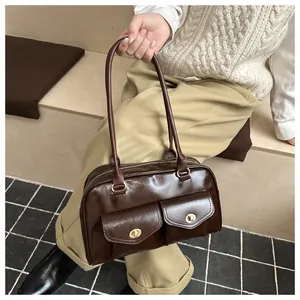 Detail of dark brown glossy square handbag with double front pockets and gold metal buckles