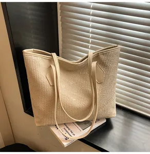 Gros plan détaillé d'un sac cabas texturé crème posé sur un livre près d'une fenêtre