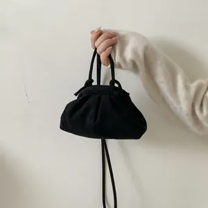 Détail d'un sac à plis noir avec texture en daim doux et bandoulières amovibles
