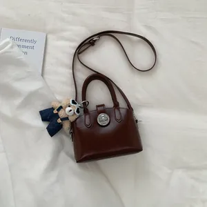 Dettaglio della borsa a mano marrone con chiusura in metallo e ciondolo a forma di orso