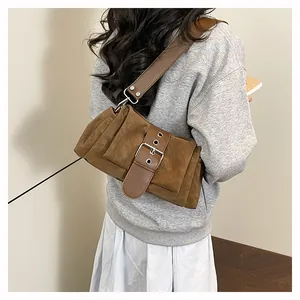 Gros plan du sac bandoulière marron en daim avec boucle argentée et détails plissés