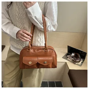 Detail of vintage caramel brown handbag with dual front pockets and gold turn-locks