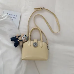 Dettaglio borsa a mano gialla con chiusura a rotazione argento e ciondolo orsetto