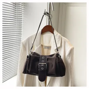 Détail du sac à main vintage marron foncé avec grande boucle argentée et lanière à œillets