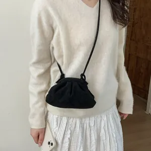 Détail d'un sac bandoulière plissé noir en suédine porté par un mannequin