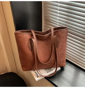 Détail d'un sac cabas marron à texture plissée sur un rebord de fenêtre sous lumière