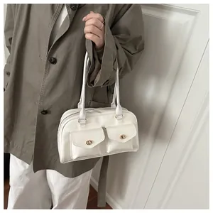 Close-up of a white leather crossbody bag featuring dual front pockets and metal locks