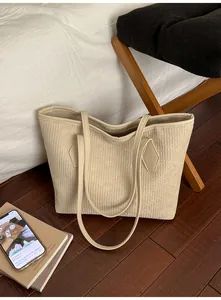 Vue détaillée d'un sac cabas beige avec des textures verticales sur un sol en bois