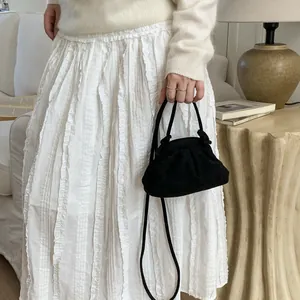 Détail d'un sac à main plissé en velours noir montrant sa texture et sa bandoulière