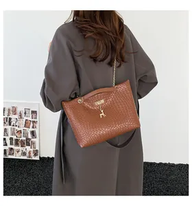 Close-up of brown woven bucket bag with gold chain strap and a delicate deer pendant