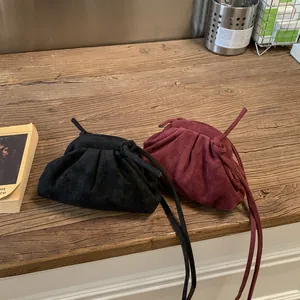 Gros plan sur des sacs nuages plissés noirs et bordeaux sur bois rustique