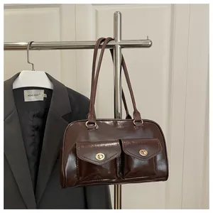 Detail of dark brown glossy pillow bag with two front pockets and gold turn-lock hardware