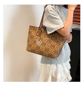 Détail du sac cabas marron avec motif à carreaux et pendentif doré en forme de lettre M