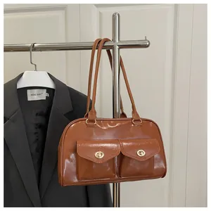 Detail of retro brown pillow bag with glossy texture and golden twist-lock pockets
