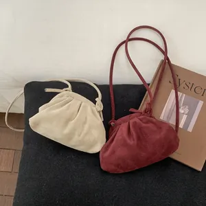 Détail de sacs à bandoulière plissés en daim crème et bordeaux avec des fines bretelles