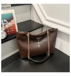 Detail view of woven brown bucket bag featuring gold chain strap and deer charm