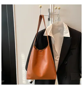 Détail d'un sac à bandoulière marron en PU avec logo Fashion doré sur fond de costume