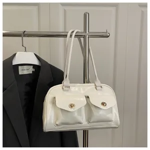 Close-up of white glossy pillow bag with dual front pockets and golden twist locks