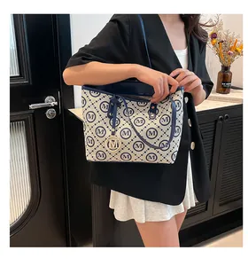 Détails du sac fourre-tout à carreaux avec pendentif M doré et anses en cuir bleu