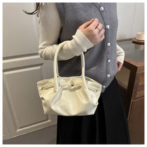 Détail du sac à main beige plissé avec boucle en métal et doubles poignées