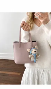 Detail of light pink lychee texture tote bag with a handmade woven bear charm