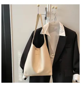 Détail du sac à bandoulière en similicuir crème avec inscription FASHION dorée sur blazer
