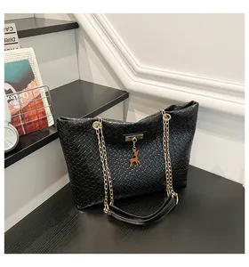 Detail of black woven bucket bag with golden chain strap and cute orange deer charm