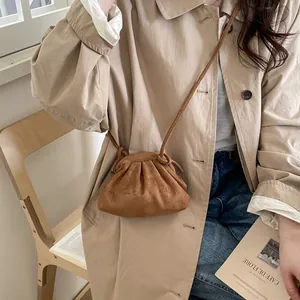 Sac bandoulière en daim caramel porté avec un trench kaki pour un style urbain élégant